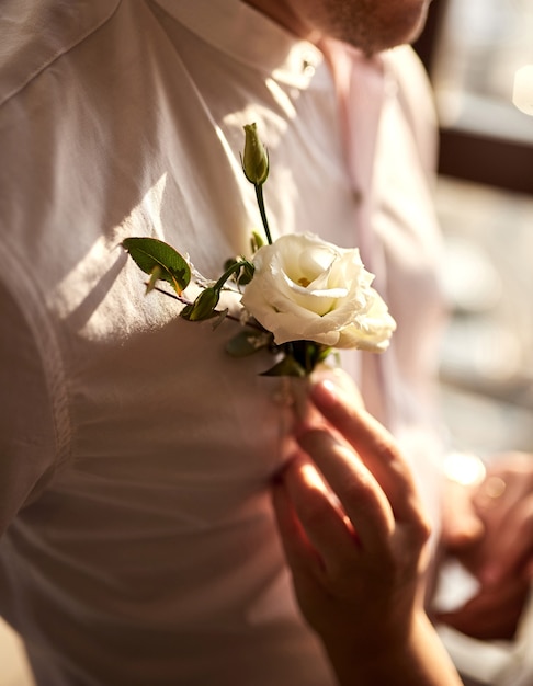 Bruid maakt de corsages van de bruidegom recht