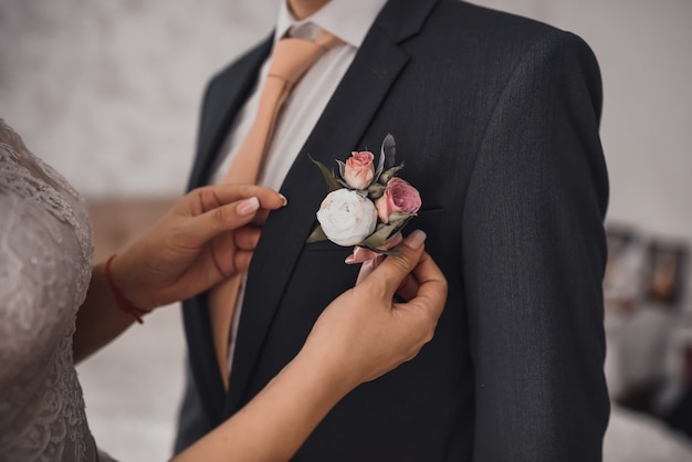 Bruid maakt een corsage aan een man vast