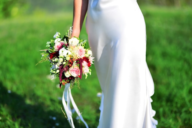 Bruid met een mooi boeket bloemen in een groene weide.