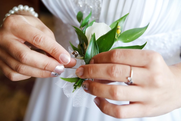 Bruid zet bruidegom op boutonniere van roze en hele roos op trouwdag