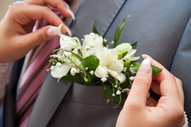 Bruid zet bruidegom op boutonniere van roze en hele roos op trouwdag