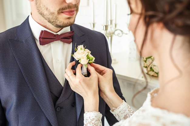 Bruid zet bruidegom op boutonniere van roze en hele roos op trouwdag