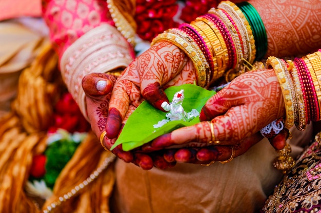 Bruidegom en bruid die groen blad en het beeldhouwwerk van Lord Ganesha in de hand houden