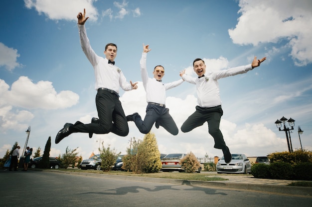 Bruidegom en groomsmen springen op het pad naar buiten