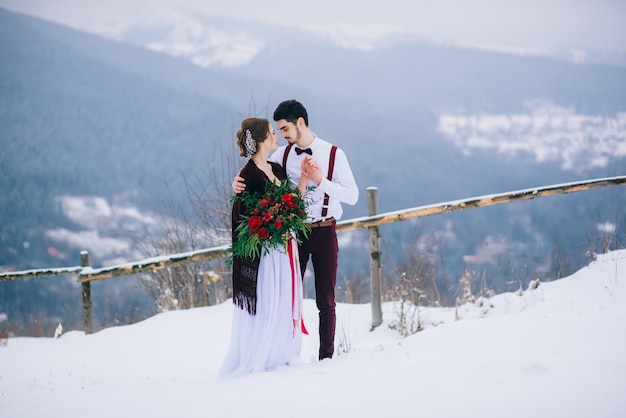 Bruidegom in een bruine en bruid in de bergen Karpaten