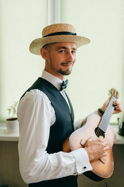 Bruidegom in landelijke stijl kleding poseren met gitaar