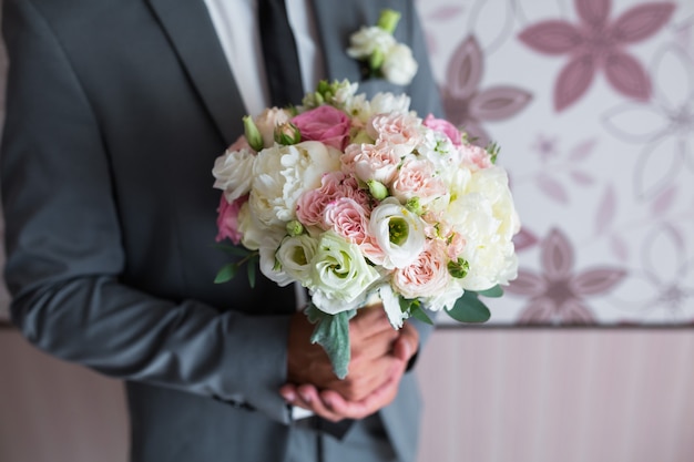 bruidegom met een bruidsboeket van witte rozen, boeket witte bloemen in mannelijke handen