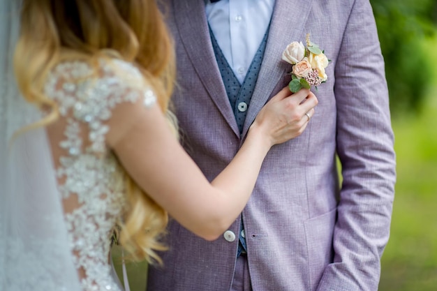 Bruiden handen spelden een kleine corsages aan een jas voor de bruidegom Floral traditionele decoratie voor bruidegom een accessoire op feestelijk trouwpak Close-up