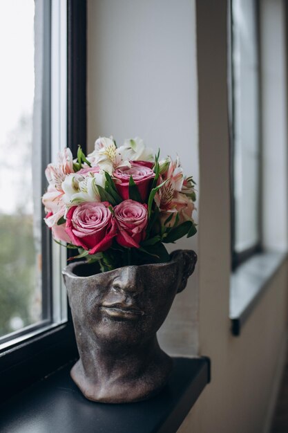 Bruids boeket rozen en pioenrozen en flesjes parfum op een witte tafel Grijze achtergrond