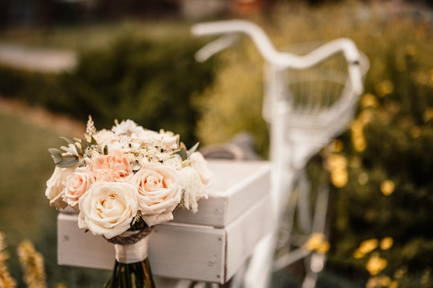 Bruidsboeket buiten de bruid in een beige jurk houdt het bloemenboeket van bloemen en groen vast