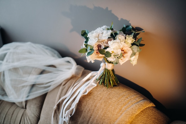Bruidsboeket met rozen op een stoel en boutonniere.Het decor op de bruiloft