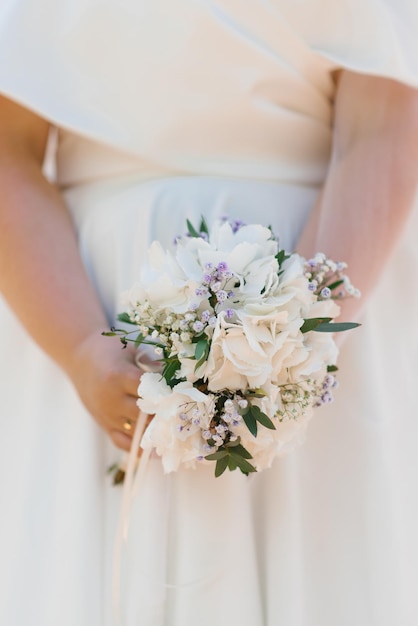 Bruidsboeket met witte hortensia in de handen van de bruid