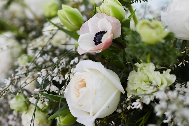 Foto bruidsboeket van exotische bloemen en groene takken. het bruidsboeket ligt op een houten tafel