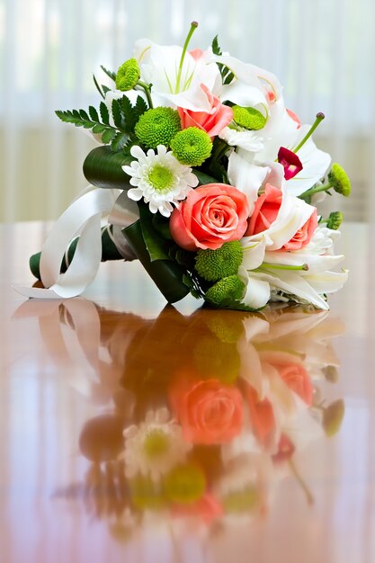 Bruidsboeket van rozen en lelies op tafel tegen de achtergrond van een helder raam