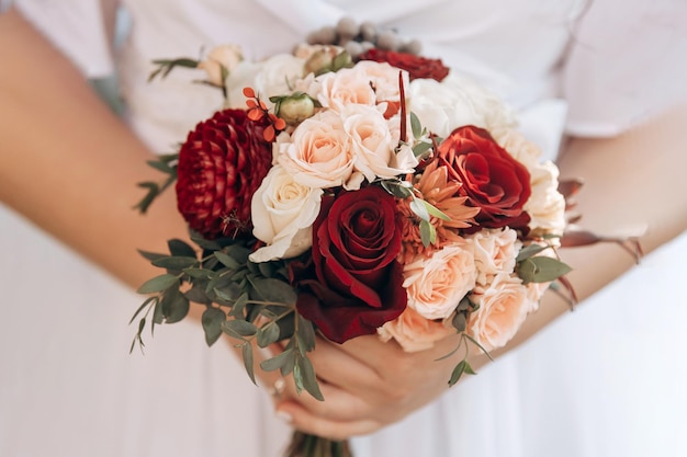 Bruidsboeket van weelderige rode en roze bloemen Witte jurk op een achtergrond