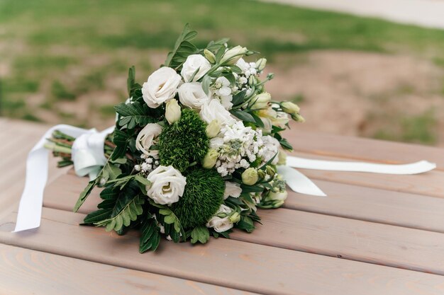 Foto bruidsboeket van witte en groene bloemen op een houten oppervlak close-up