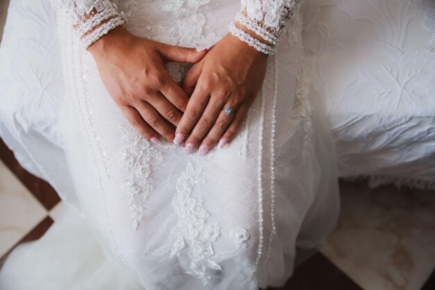 Foto bruidshanden op jurk met mooie nagels en verlovingsring