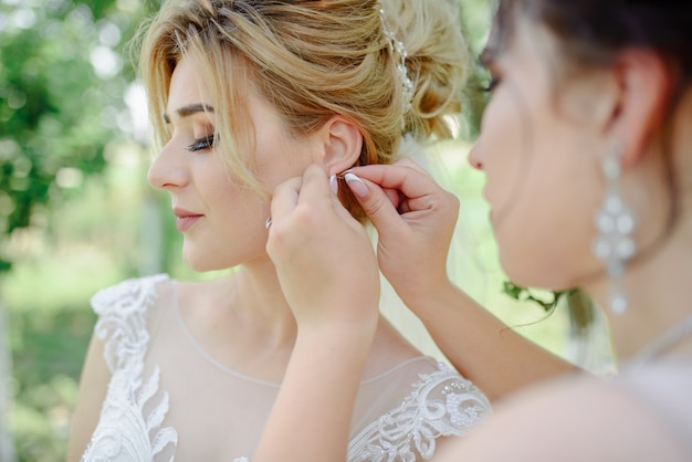 Bruidsmeisje helpt de bruid haar oorbellen om te doen