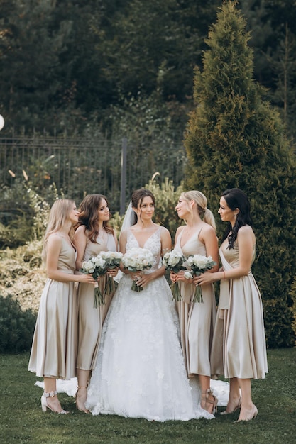 Bruidsmeisjes in pastelkleurige jurken staan buiten bij de bruid.