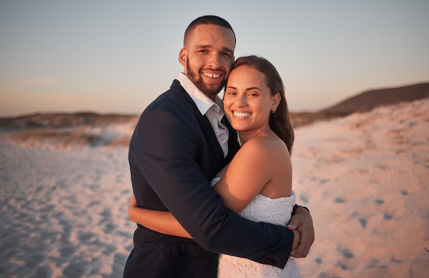 Bruidspaar en liefde op het strand bij zonsondergang met een bruid en bruidegom voor ceremonie inzet en viering Jonggehuwden man en vrouw omhelzen en knuffelen op het zand voor huwelijk en romantisch zijn