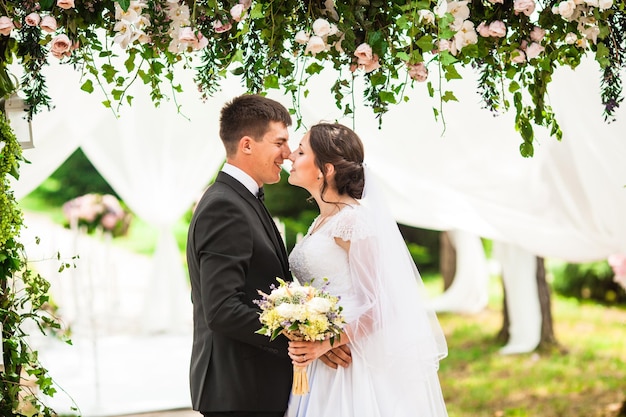 Bruidspaar onder de bloemenboog bij de huwelijksceremonie
