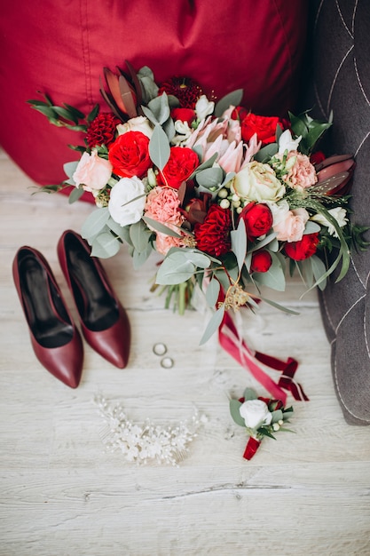 Bruidsschoenen met een boeket met rozen en andere bloemen op de fauteuil