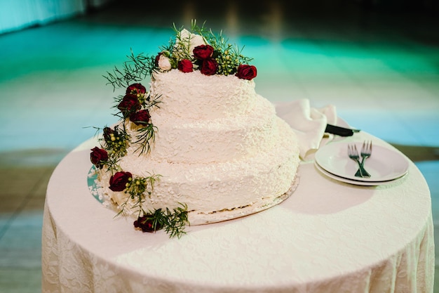 Bruidstaart Een klassieke gelaagde witte taart gedecoreerd met bloemen op tafel