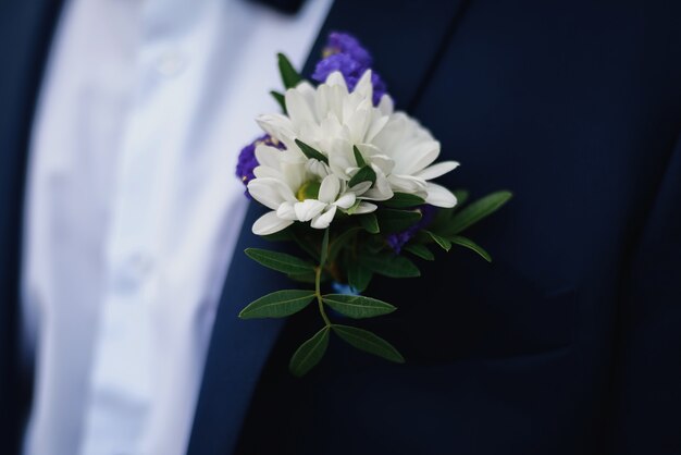 Bruiloft boutonniere van margrieten op de blauwe jas van de bruidegom