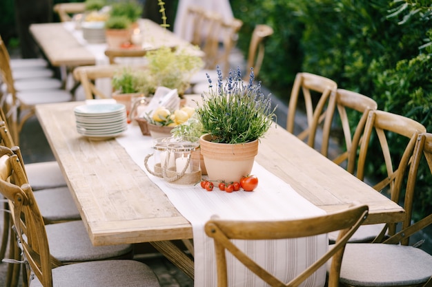 Bruiloft diner tafel receptie bij zonsondergang buiten oude rechthoekige houten tafels met voddenloper