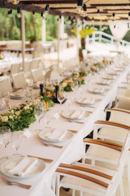 Bruiloft diner tafel receptie een lange tafel met een wit tafelkleed een krans met gloeilamp