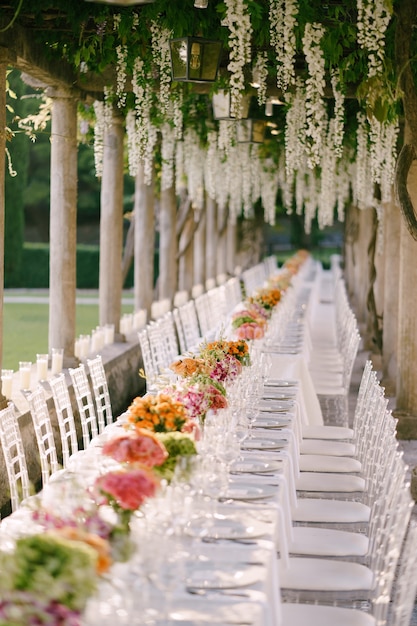 Bruiloft eettafel receptie een zeer lange tafel voor gasten met een wit tafelkleed bloemen