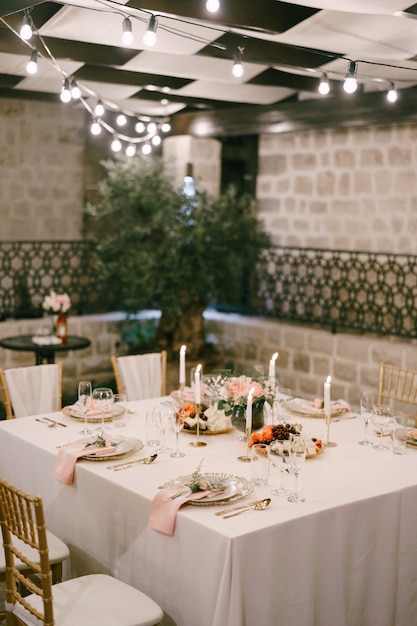 Bruiloft eettafel receptie rechthoekige tafel voor zes personen met een wit tafelkleed en roze