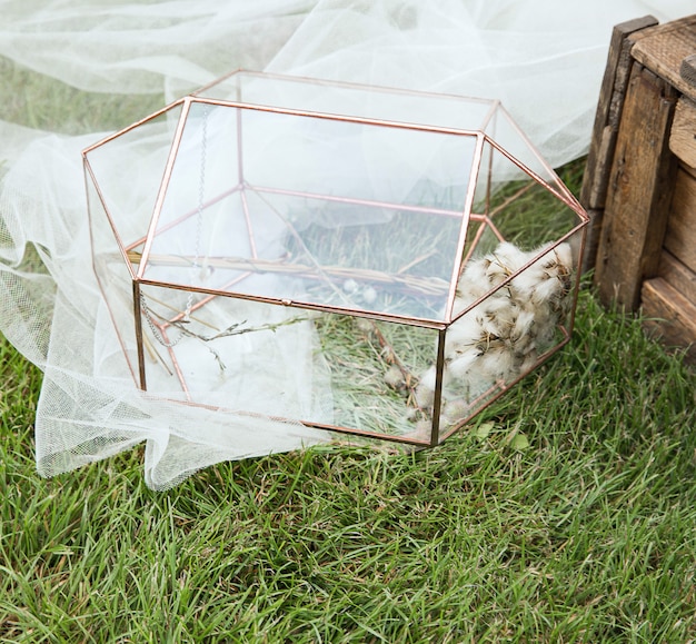 Bruiloft glazen doos voor enveloppen voor groeten op houten tafeltje en het witte weefsel met planten als decoratie