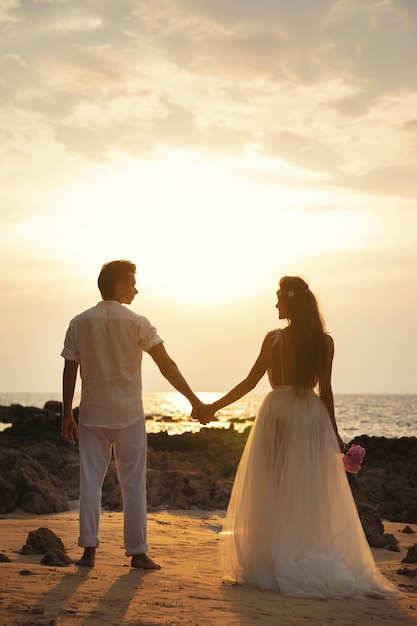 Bruiloft op het strand - Jonge echtpaar hand in hand