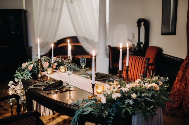 Bruiloft tafeldecoratie met bloemen op de tafel in het kasteel, tafeldecoratie voor het diner bij kaarslicht. Diner met kaarsen.