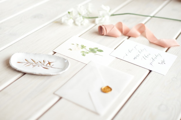 Bruiloft uitnodiging verjaardag cadeaubon voor een spa of zorg ingericht briefkaart op een witte houten tafel met een tak van witte bloemen.