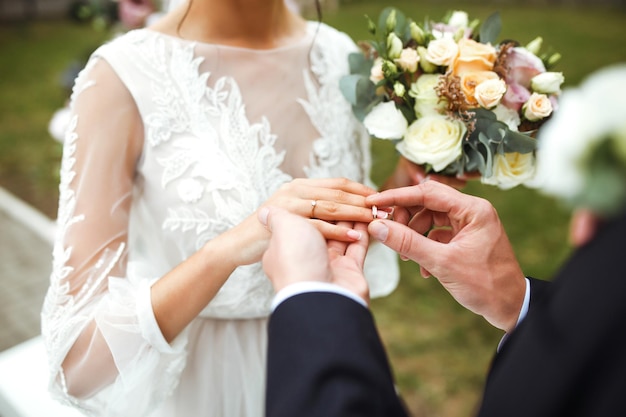 Foto bruiloft verlovingsringen bruidegom zet een ring aan de vinger van zijn mooie vrouw concept bruiloft details.