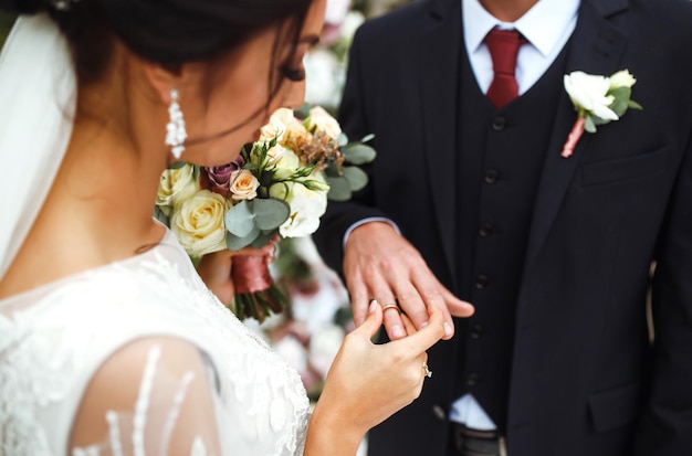 Bruiloft verlovingsringen Bruidegom zet een ring aan de vinger van zijn mooie vrouw Concept bruiloft details.