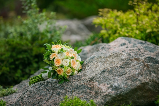 Bruiloftsboeket van bloemen en groen met lint ligt op een rots op een achtergrond van groen Bruiloftsdecoraties