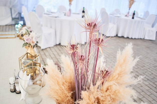 Bruiloftsdecoratie in boho-stijlLichte kleuren in de tentTrouwtafel versierd met pampagras Rozen en gouden geometrische kandelaars