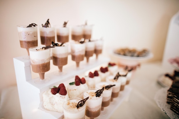 Foto bruiloftsdesserts taarten snoepjes op de desserttafel tijdens de huwelijksceremonie