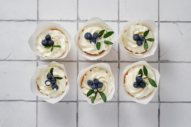 Bruiloftsvoorbereidingen Witte bruidscupcakes versierd met verse bosbessen, kruiden en bloemen