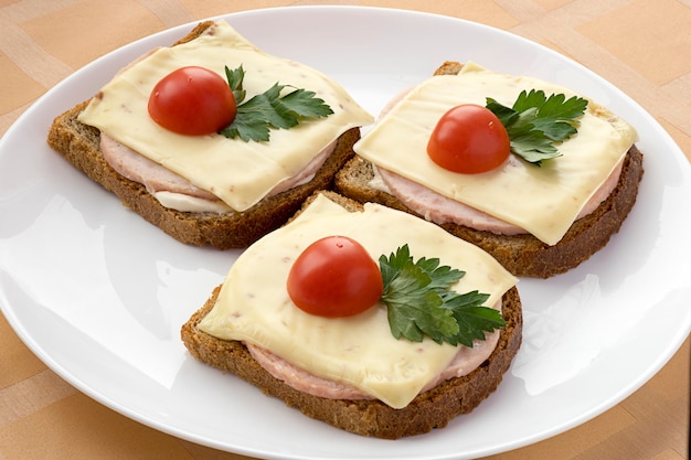 Bruin brood met ham en kaas met tomaten.