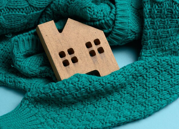 Foto bruin houten model van het huis is verpakt in een warme gebreide trui leenconcept voor huisisolatie alternatieve energie