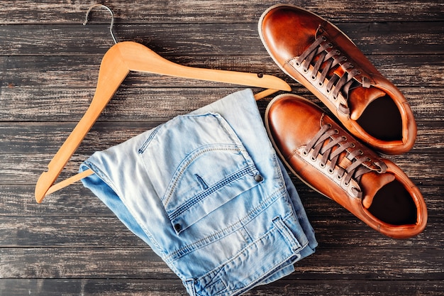 Bruin lederen casual schoenen en jeans op donker houten bovenaanzicht. Mode concept