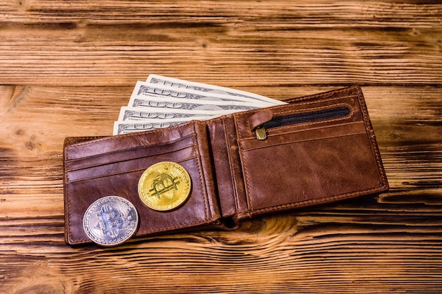 Bruin lederen portemonnee bitcoins en honderd dollar biljetten op de houten achtergrond