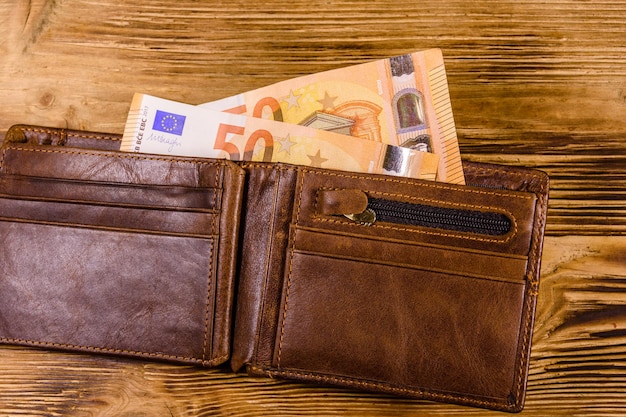Foto bruin lederen portemonnee met vijftig euro bankbiljetten op de houten achtergrond top view