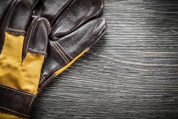 Bruin lederen veiligheidshandschoenen op houten bord.