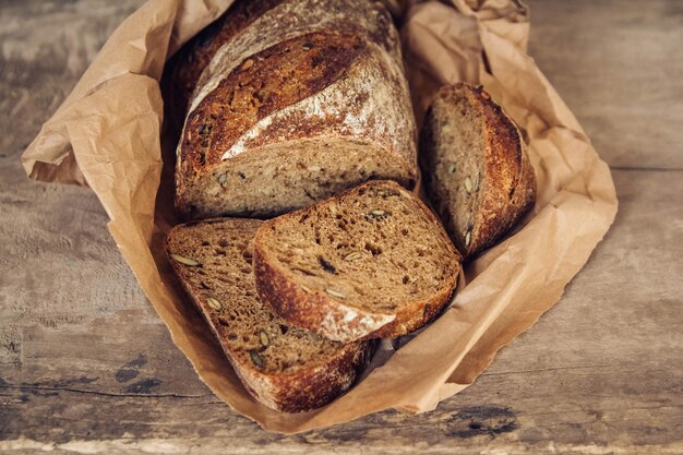 Bruin vers brood met zaden wordt in stukjes gesneden op een oude houten ondergrond. Bovenaanzicht, kopieer ruimte