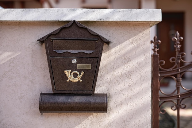 Bruine brievenbus op moderne huismuur met ijzeren hek. Postbus, postbezorging